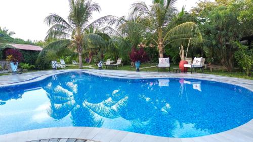 a blue swimming pool with palm trees in the background at Mama Africa Art Residence & Art Center Gambia in Tanji