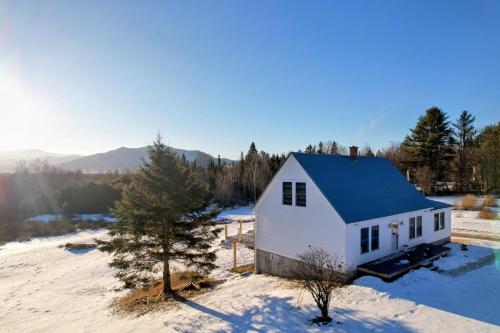 a white house with a blue roof in the snow at 64J Stunning views, close to attractions! 20 min to Bretton Woods. Pool & gym passes! in Whitefield