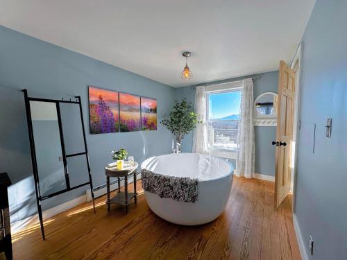 eine große Badewanne in einem Zimmer mit Fenster in der Unterkunft 64J Stunning views, close to attractions! 20 min to Bretton Woods. Pool & gym passes! in Whitefield