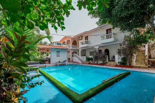a pool in front of a house with trees at Baga Galaxy in Baga