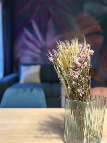 un vase en verre avec des fleurs assis sur une table dans l'établissement Appartement cosy - Quartier Saint-Georges - 4P, à Paris