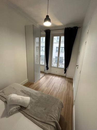 um quarto com uma cama e uma grande janela em Cosy Appartement in Quartier Saint-Georges - 4P em Paris