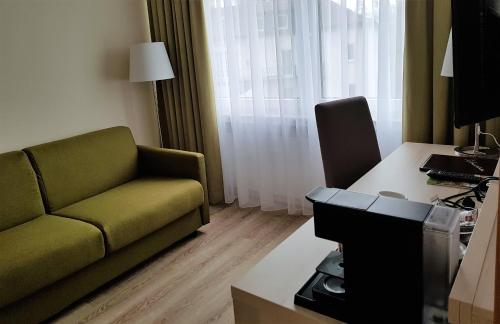 a living room with a green couch and a desk at ParkHotel Bad Harzburg in Bad Harzburg