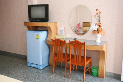 a room with a table with a small refrigerator and a mirror at Soda Resort in Kamphaeng Phet