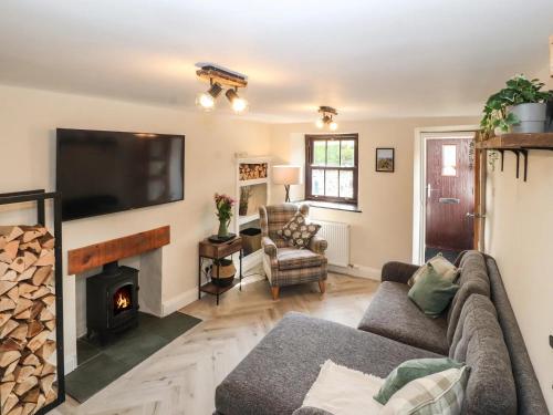 ein Wohnzimmer mit Couch und Kamin in der Unterkunft Fellside Cottage in Shap