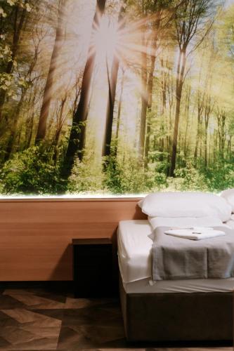 a bedroom with a large painting of a forest at Park Hotel Sóstó in Nyíregyháza