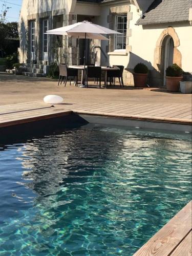 une piscine avec une table et un parasol dans l'établissement Villa chic à Plouigneau avec piscine privée, à Plouigneau