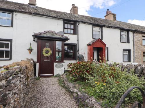 une maison blanche avec une porte rouge dans l'établissement Fellside Cottage, à Shap