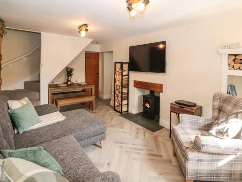 - un salon avec un canapé et une cheminée dans l'établissement Fellside Cottage, à Shap