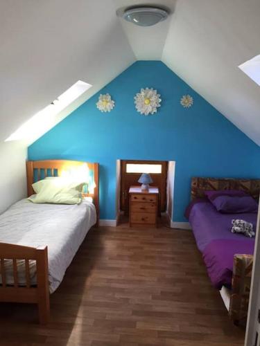 Cette chambre comprend 2 lits et un mur bleu. dans l'établissement Meublé sur l'ILE DE TASCON à 300 m de la plage, à Saint-Armel