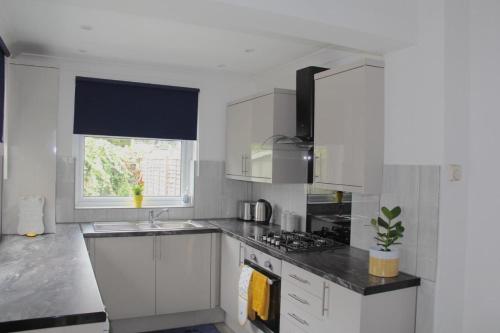 a kitchen with white cabinets and a sink and a window at Gresham House - London Excel in London