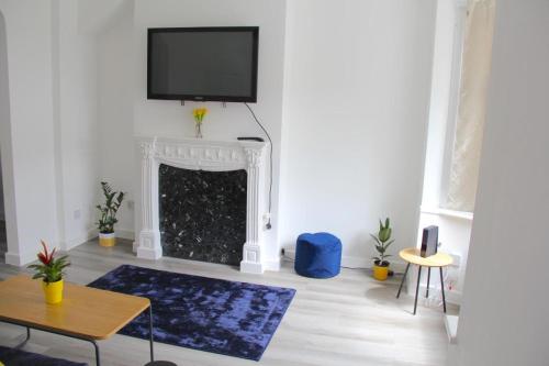 a living room with a fireplace with a tv on the wall at Gresham House - London Excel in London