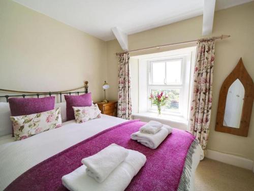 a bedroom with a purple bed with towels on it at Beautiful family home, sea views, large garden in Port Isaac