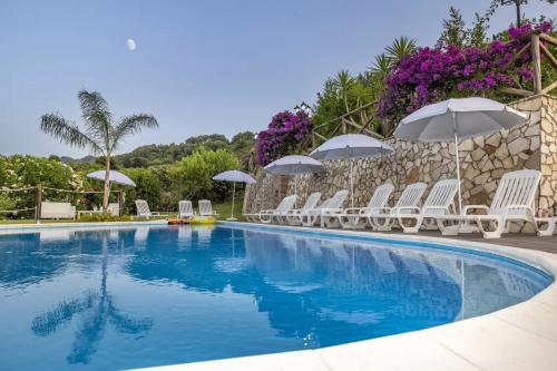 a swimming pool with white chairs and umbrellas at Arcaloro Resort Rooms Ghiro in SantʼAngelo di Brolo