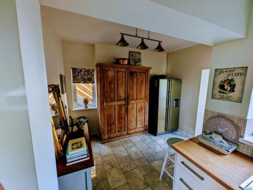 a kitchen with a wooden cabinet and a refrigerator at Cartref, 1860s family home. in Bridgend