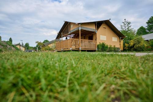 a house with a deck in a field of grass at Glamping Nieuw Heeten in Nieuw-Heeten