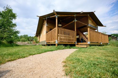 a house with a large deck on a grass field at Glamping Nieuw Heeten in Nieuw-Heeten