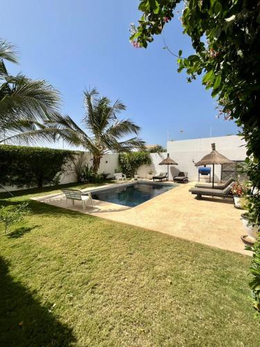 a backyard with a swimming pool and palm trees at La Baraka, extravagant villa for 8 with pool in Saly in Gandigal