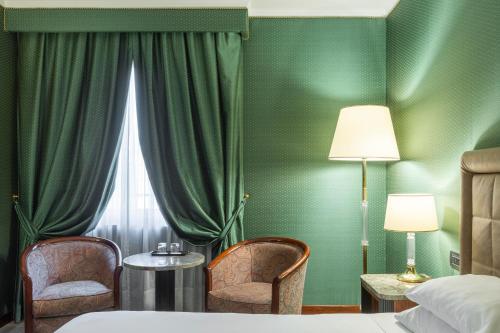a bedroom with green walls and two chairs and a bed at Doria Grand Hotel in Milan
