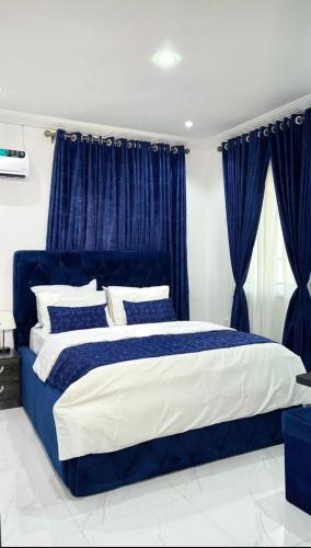 a blue and white bed in a bedroom with blue curtains at 1bedroom serviced apartment in Benin City in Benin City