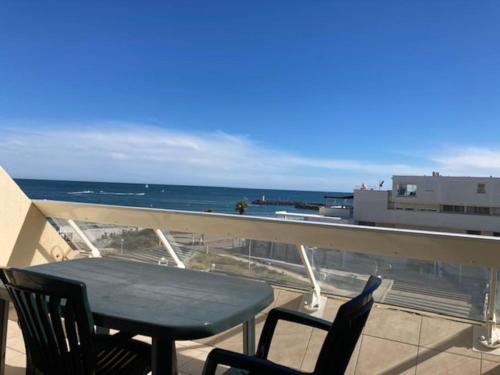 une table et des chaises sur un balcon avec l'océan dans l'établissement Studio 2, Héliopolis D au village naturiste, au Cap d'Agde