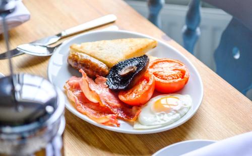 a plate of food with eggs bacon tomatoes and toast at The Bell Inn in Walberswick