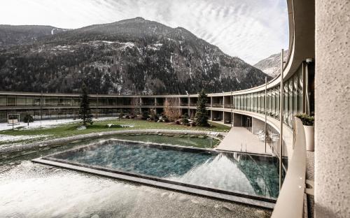 ein Gebäude mit einem Pool und einem Berg in der Unterkunft OLM Nature Escape - Eco Aparthotel in Sand in Taufers