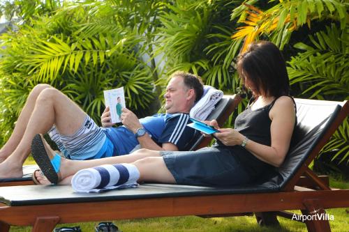 a man and a woman sitting on a bench reading at Airport Villa in Katunayake