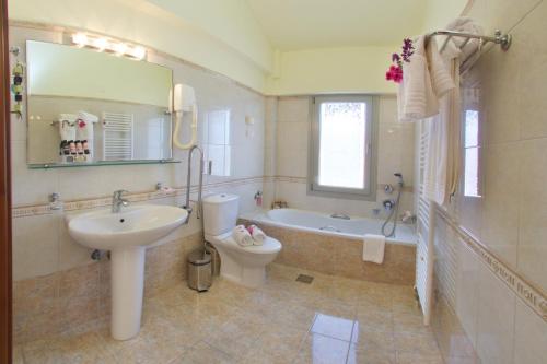 a bathroom with a sink and a toilet and a tub at Belle View Hotel - Sea View & Sunset in Mánganos