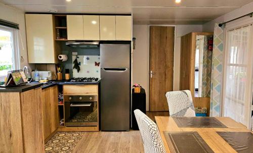 une cuisine avec un réfrigérateur en acier inoxydable et une table dans l'établissement Mobil home 653 tout confort 2ch au camping La Réserve, à Gastes
