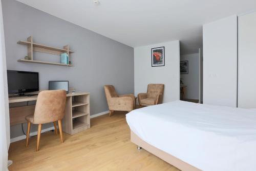 a bedroom with a bed and a desk with chairs at KOSY Appart'Hôtels - La Maison Des Chercheurs in Vandoeuvre-lès-Nancy
