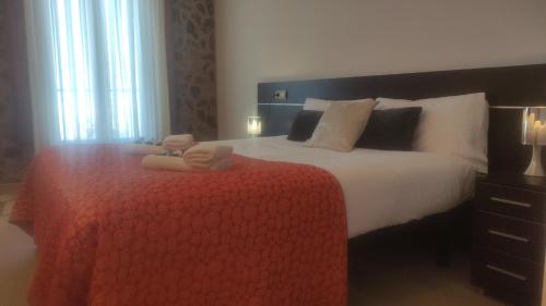 a bedroom with a large bed with a red blanket at Hostal Bavieca in Medinaceli