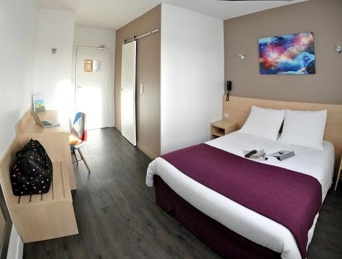 Habitación de hotel con cama grande y escritorio. en Logis hôtel restaurant la Haute Forêt en Vertou