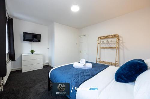 um quarto com uma cama azul e branca e uma televisão em Luxurious & Spacious 2 Bedroom Home By Opuluxe Properties Short Lets & Serviced Accommodation Near Manchester City Center em Manchester