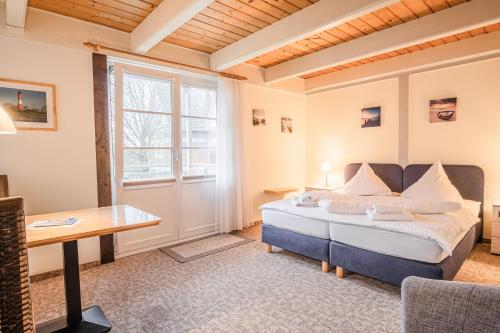 1 dormitorio con cama, escritorio y ventana en Haus Möwe, en Pellworm