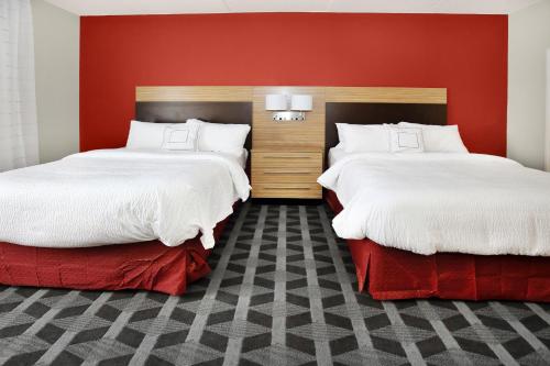 2 camas en una habitación con paredes rojas en TownePlace Suites by Marriott Grove City Mercer/Outlets, en Grove City