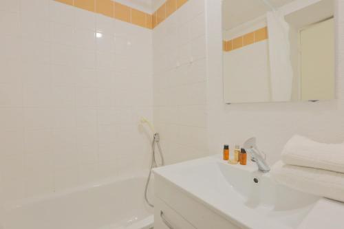 a white bathroom with a sink and a tub at KOSY Appart'Hôtels - La Maison Des Chercheurs in Vandoeuvre-lès-Nancy