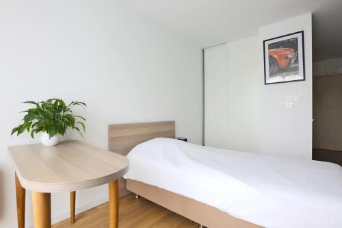 a bedroom with a bed and a table with a plant at KOSY Appart'Hôtels - La Maison Des Chercheurs in Vandoeuvre-lès-Nancy