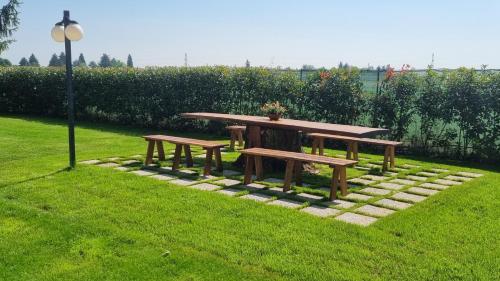a picnic table and two benches on a lawn at HOTEL AI TIGLI in Langhirano