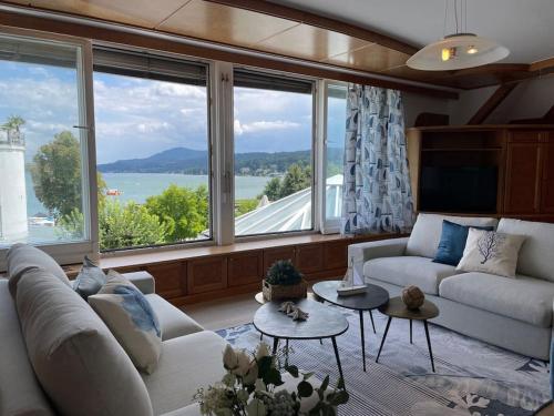 a living room with a white couch and a large window at Lakeside Serenity in Velden am Wörthersee