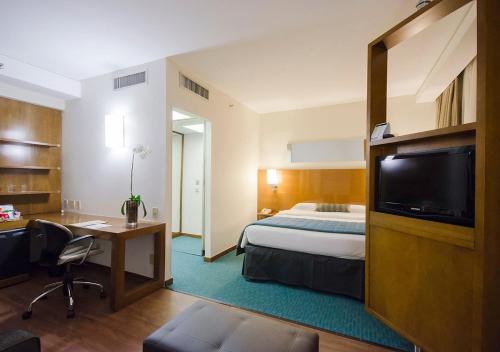a hotel room with a bed and a desk and a tv at Estanplaza Berrini in Sao Paulo