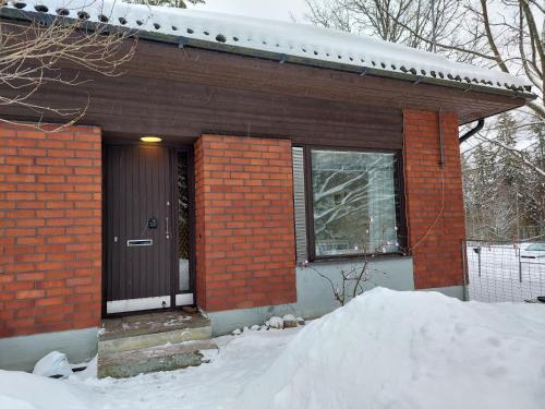 a brick house with a black door in the snow at Wera in Porvoo