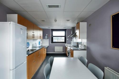 a kitchen with a table and a white refrigerator at Ian Baker House in London