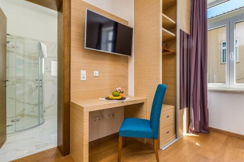 a bathroom with a desk with a blue chair and a television at Tolle Unterkunft mit Pool in Strandnähe in Crikvenica