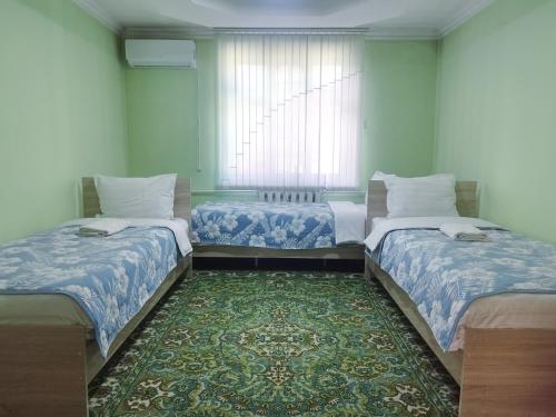 a room with two beds and a rug at Uyut house Osh in Osh