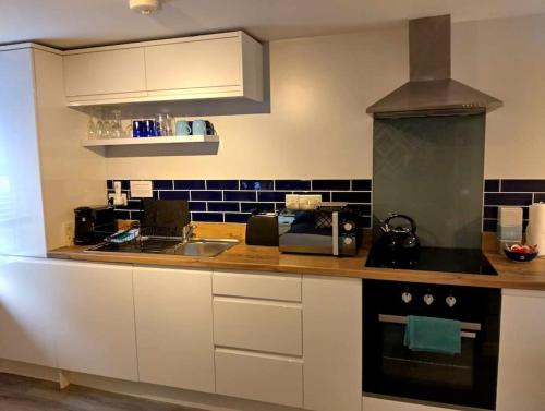 a kitchen with white cabinets and a sink and a stove at Smart modern studio flat in central Bournemouth in Bournemouth