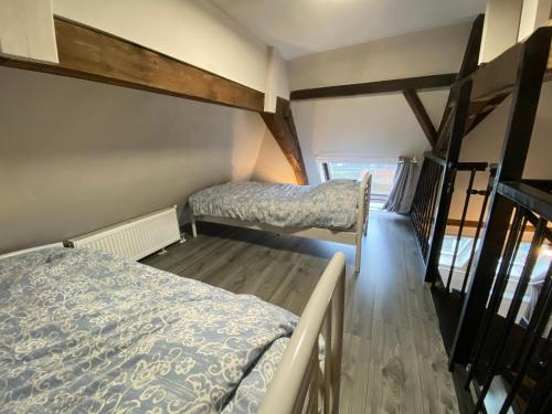Habitación pequeña con 2 camas y suelo de madera. en Luxe en ruim appartement in Rijksmonument, en Vianen