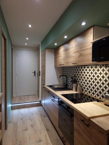 - une cuisine avec des placards en bois et une porte blanche dans l'établissement Cosy Haven 5 min from Nice Carnival Hyper-Center!, à Nice