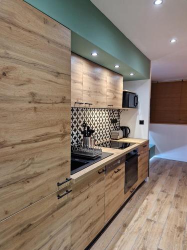 une cuisine avec des armoires en bois et un four à plaques de cuisson dans l'établissement Cosy Haven 5 min from Nice Carnival Hyper-Center!, à Nice