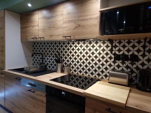 - une cuisine avec du carrelage noir et blanc sur le mur dans l'établissement Cosy Haven 5 min from Nice Carnival Hyper-Center!, à Nice